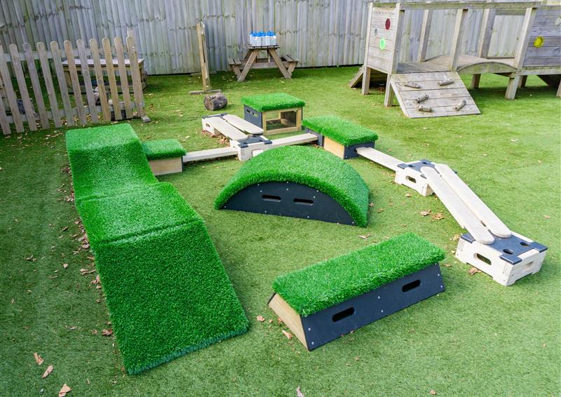 8 blocks from a Get Set, Go! Blocks set and 7 wooden planks and 4 wooden blocks from the Play Builder set are placed together on artificial grass. All of this is included in the Sports Premium Adventurer package.